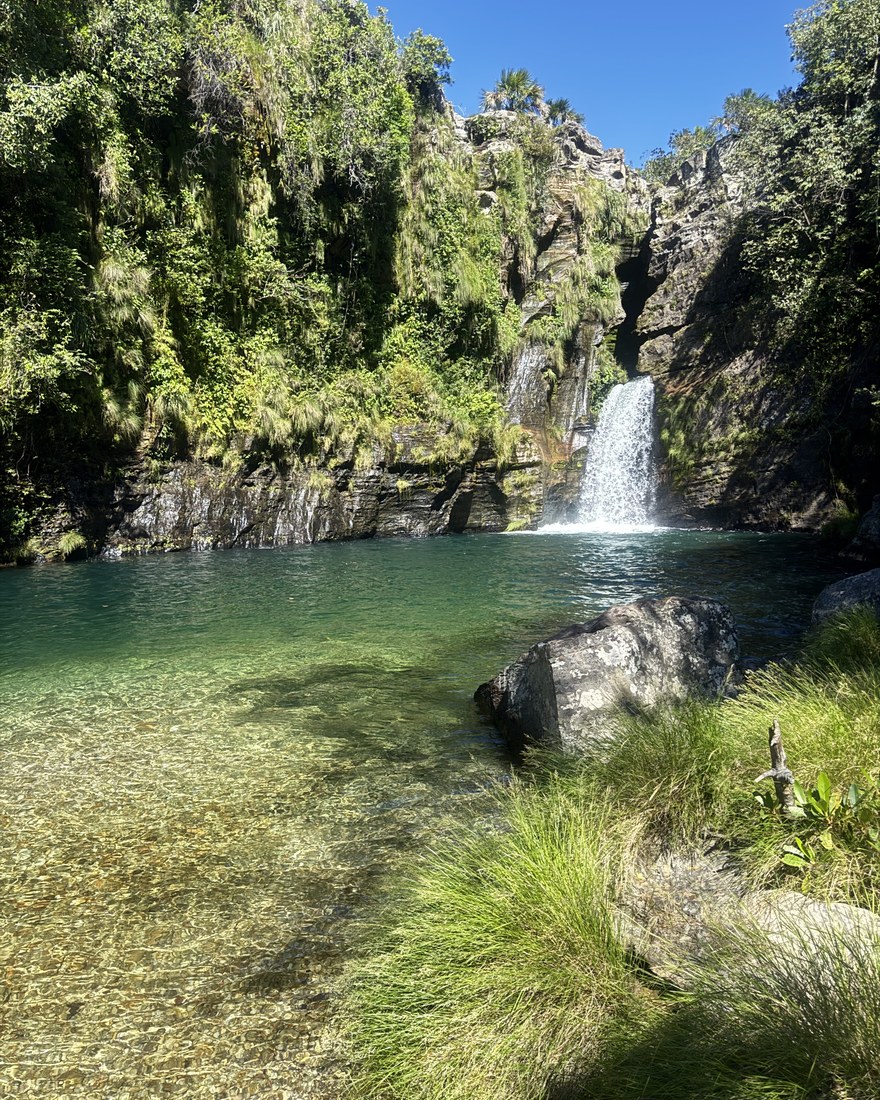 Poço de água esmeralda ao pé de uma cachoeira, cercado de mata