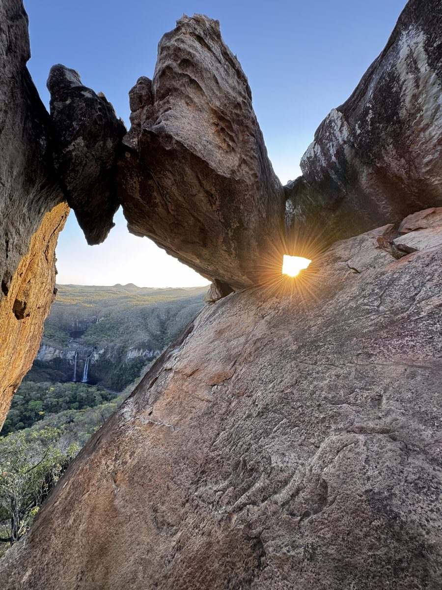Sol atravessando a fresta de uma formação rochosa em arco