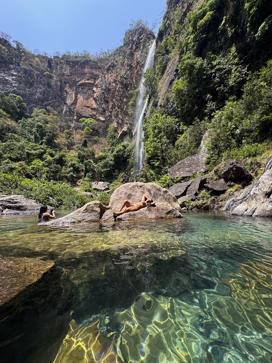 Poço de água esmeralda e cristalina logo abaixo de uma cachoeira