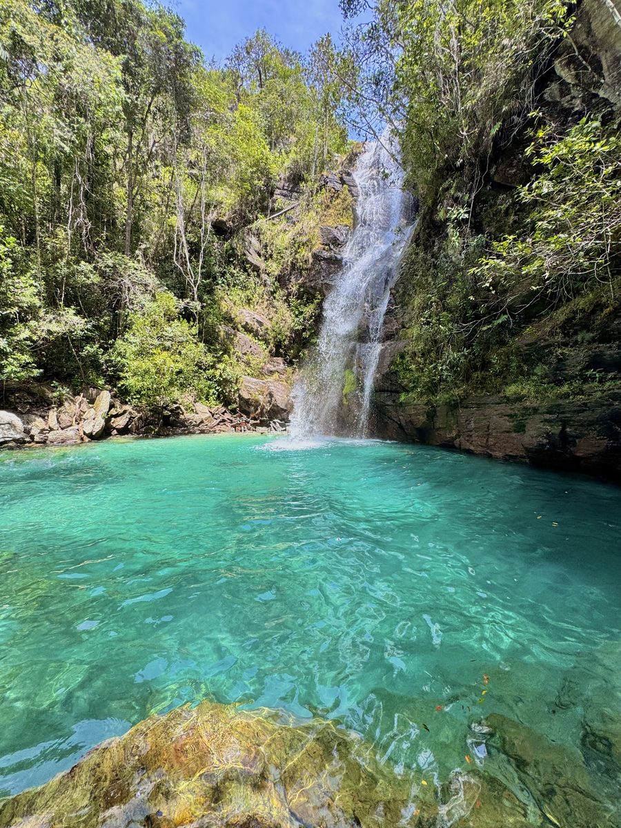 Poço de água turquesa vibrante ao pé de uma cachoeira