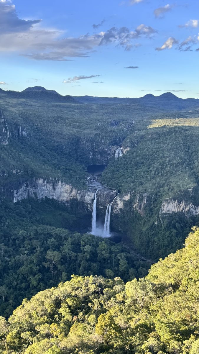 Vista ampla de um cânion do cerrado com uma cachoeira distante