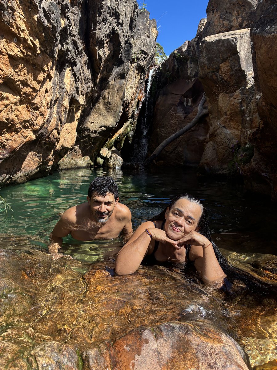 Visitantes relaxando em piscina natural entre pedras