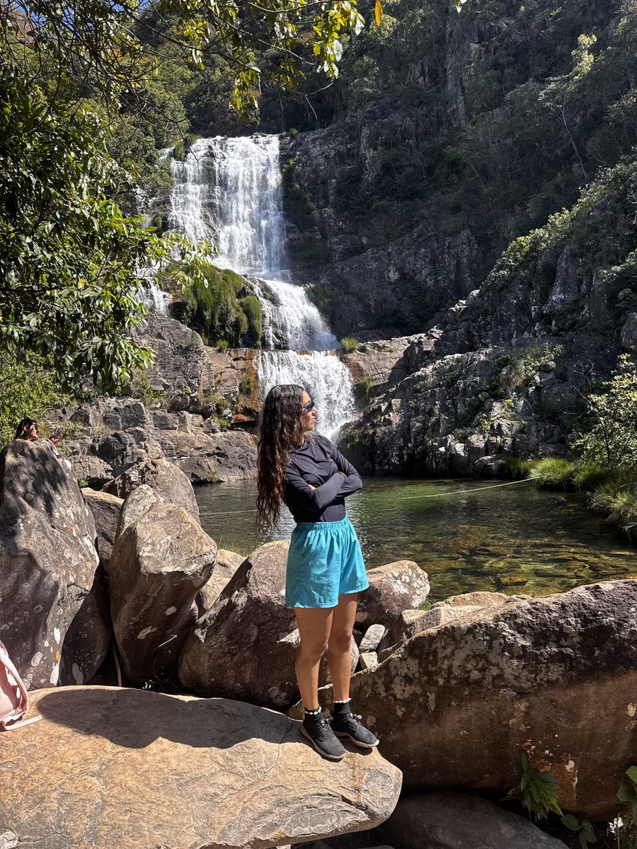 Mulher sobre as pedras contemplando uma cachoeira na Chapada